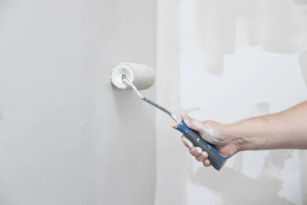 Man with roller painting wall. Close up of house paint roller. Home repairs with family. Update, improvement living room.