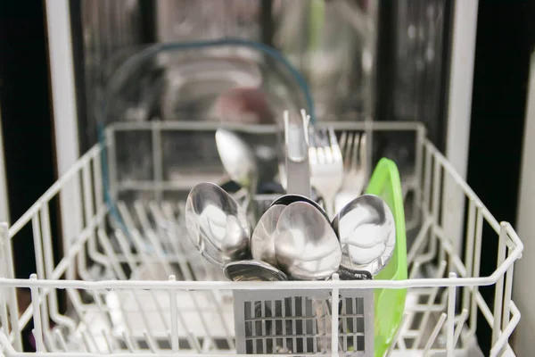 Open dishwasher with white clean dishes after washing in kitchen