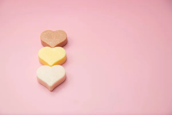 Heart shaped pink bar of soap on a light pink background. Top view, copy space. Heart shaped soaps. Importance of personal hygiene care. Copy space