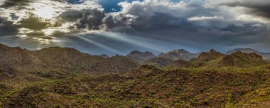 Arizona 'nın Sonora Çölü üzerindeki dramatik ışıklandırma ve engebeli araziyle muson yağmurlarının hava aracı görüntüsü..