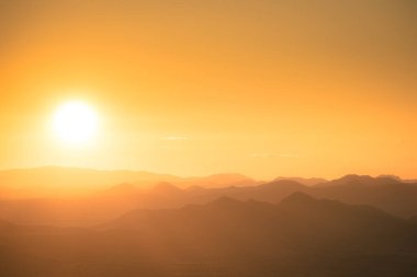Arizona 'daki Sonoran Çölü' nün arkasında güneş batıyor. Havası altın ışıkla aydınlanıyor. Dağlar siluetle aydınlanıyor..