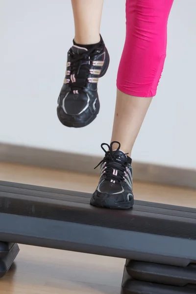 Close up of feet in step equipment at gym — Stock Photo, Image