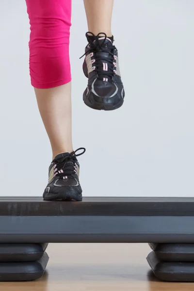 Close up of feet in step equipment at gym — Stock Photo, Image