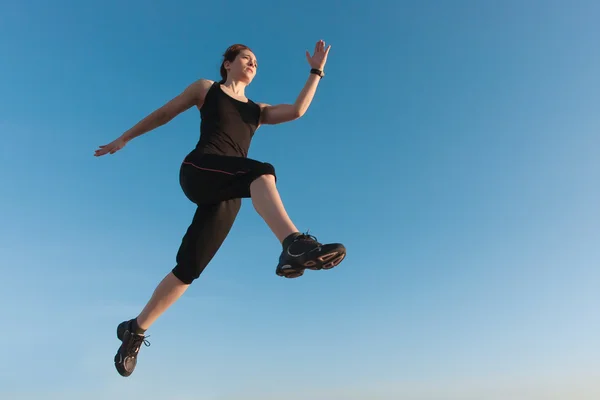 バック グラウンドで青い空とジャンプの女性に合わせて — ストック写真