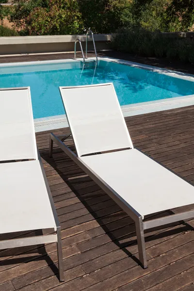 Witte ligstoelen in de buurt van een pool met bomen op achtergrond — Stockfoto