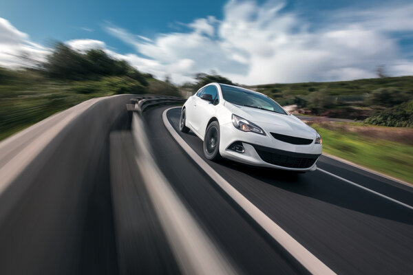 White car cornering in mountain road with speed blur Stock Photo