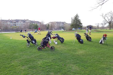 Çocuklar ve yetişkinler, yerel bir golf sahasında, ilkbaharın erken saatlerinde golf sahasında sıcak bir akşamın tadını çıkarırlar..