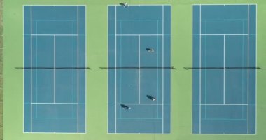 Dört tenisçi yaz aylarında bir park bölgesi tenis kortunda birbirlerine karşı gösteri yapıyorlar..