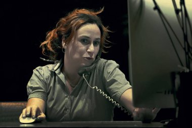 Sekreter telefona cevap verir ve müşterilerle konuşur. Masaüstünde oturur ve bilgisayarla çalışır. Aynı anda bir sürü telefon görüşmesi. Gece vakti.