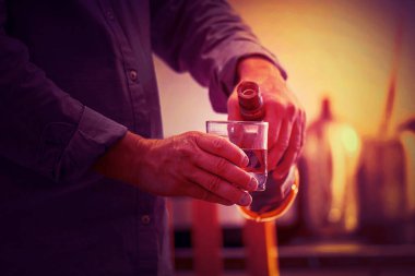 Mutfakta viski şişesi olan yaşlı beyaz bir adamın elleri. Sarhoşluk ve alkolizm kavramı. Alkolik baba. Tonlama