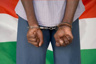 Macaristan bayrağının arka planında kelepçeli bir Afrikalı. Arkadan bak. Macaristan 'da cezaevi ve yolsuzluk kavramı