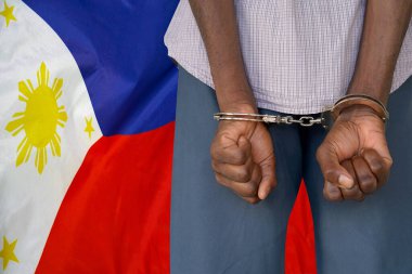 Filipinler bayrağının arka planında kelepçeli bir Afrikalı. Arkadan bak. Filipinler 'de cezaevi ve yolsuzluk kavramı