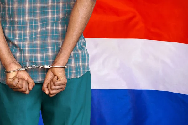 打着荷兰国旗背景上戴手铐的非洲男子 后视镜荷兰监狱与腐败的概念 — 图库照片