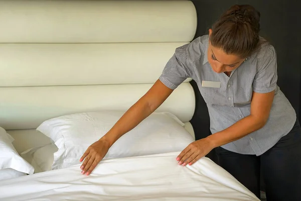 一个年轻的女佣在酒店房间里铺床 管家铺床 — 图库照片