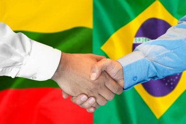 İki bayrağın arka planında iş tokalaşması. Erkek tokalaşması Litvanya ve Brezilya bayrağının arka planında. Destek konsepti