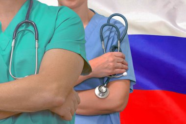 Yakın plan tıbbi ekip çalışanı ve Rusya bayrağı geçmişi olan kadın ve erkek cerrahlar. Rusya 'da profesyonel cerrahi. Rusya 'daki tıbbi teknoloji araştırma enstitüsü ve doktor servis konsepti