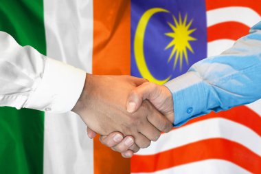 İki bayrağın arka planında iş tokalaşması. İrlanda ve Malezya bayrağının arka planında erkek tokalaşması. Destek konsepti