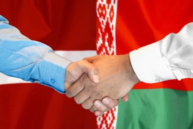 İki bayrağın arka planında iş tokalaşması. Beyaz Rusya ve Letonya bayrağının arka planında el sıkışan erkekler. Destek konsepti