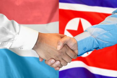 İki bayrağın arka planında iş tokalaşması. Lüksemburg ve Kuzey Kore bayrağının arka planında erkek tokalaşması. Destek konsepti