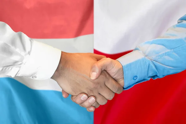 2つのフラグを背景にビジネス握手 ルクセンブルクとポーランドの国旗を背景に男性が握手をする サポートコンセプト — ストック写真