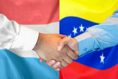 İki bayrağın arka planında iş tokalaşması. Lüksemburg ve Venezuela bayrağının arka planında erkek tokalaşması. Destek konsepti