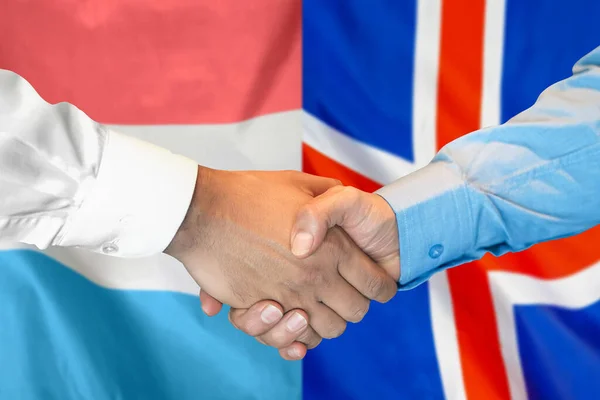 在两面旗帜的背景下进行商业握手 男子在卢森堡和冰岛国旗的背景下握手 支助概念 — 图库照片