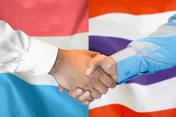 2つのフラグを背景にビジネス握手 ルクセンブルクとタイの国旗を背景に男たちが握手 サポートコンセプト — ストック写真