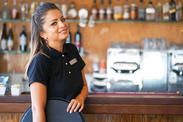 Portrait of waitress standing near the restaurant bar of the hotel. A waitress with a tray is waiting for the order
