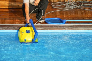 Bakım robotu temizler. Otel çalışanı havuzu temizliyor. Otomatik havuz temizleyicileri