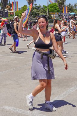 Hoşgörü gösterisinde gökkuşağı bayraklı neşeli genç kız kalabalığın önünde. Geleneksel LGBT geçit töreni. 10 Haziran 2022. Tel Aviv 'de. İsrail