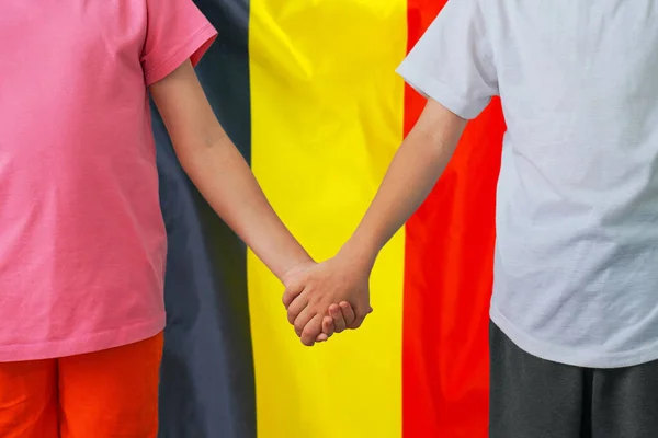 Two children joined hands on flag Belgium background. Boy and girl joined hands on background flag of Belgium. Concept of family and parenting in Belgium