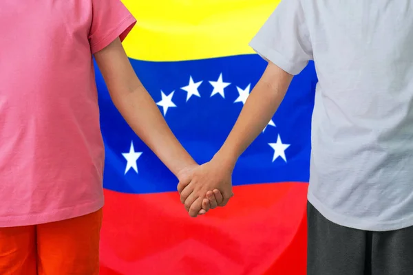 Two children joined hands on flag Venezuela background. Boy and girl joined hands on background flag of Venezuela. Concept of family and parenting in Venezuela