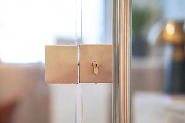 Door lock and doorknob on close glass door in office. Detail of contemporary door lock with doorknob for a glass door in office