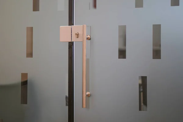 Door lock and doorknob on close glass door in office. Detail of contemporary door lock with doorknob for a glass door in office