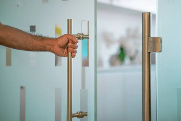 Male hand open the office glass door. Male hand open glass door. Man hand prepare to open glass door to entering an office background