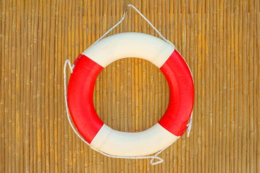 Kırmızı can simidi yüzüğü, acil durum için bir bambu duvarına asılıydı. İnsanlar suya daldığında, neredeyse havuz ve plaja yakın bir yerde. Yüzme havuzunda hayat yüzüğü