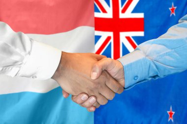 Business handshake on background of two flags. Men handshake on background of Luxembourg and New Zealand flag. Support concept