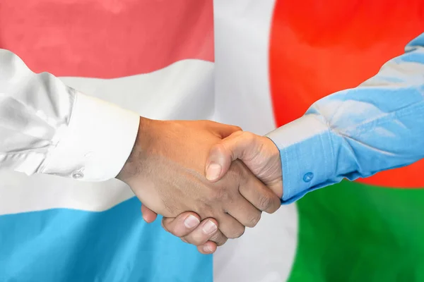 Рукостискання Тлі Двох Прапорів Чоловіче Рукостискання Тлі Прапора Люксембургу Мадагаскару — стокове фото