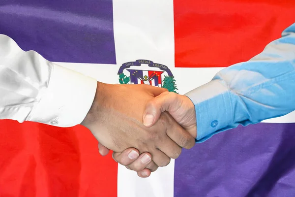 Business handshake on Dominican Republic flag background. Men shaking hands on Dominican Republic flag background. Support concept in Dominican Republic