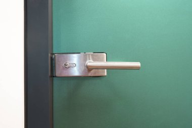 Door lock and doorknob on close glass door in office. Detail of contemporary door lock with doorknob for a glass door in office