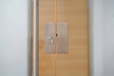 Door lock and doorknob on close glass door in office. Detail of contemporary door lock with doorknob for a glass door in office