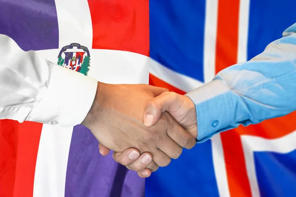 在两面旗帜的背景下进行商业握手 男子握手背景多米尼加共和国和冰岛的国旗 支助概念 — 图库照片