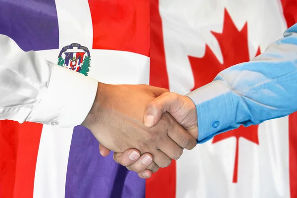 在两面旗帜的背景下进行商业握手 男子握手背景多米尼加共和国和加拿大国旗 支助概念 — 图库照片