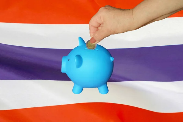 タイの国旗を背景に貯金箱に硬貨を入れる高齢女性の手 手は貯金箱にコインを入れる 退職金貯金 貯金箱 タイにおけるお金と退職金の節約 — ストック写真