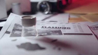 Masanın üzerinde kamera ve klasörlerin yanındaki gizli belge. Gizli çok gizli bilgiler ya da devlet kurumundaki gizli belgeler ya da basın ya da casusluk şebekesine sızan casuslar.