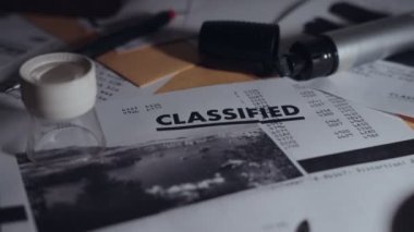 Işık, ofis masasında gizli belgeleri göstererek karanlıktan aydınlığa çıkıyor. Çok gizli bilgi ve fotoğraf sırları açığa çıkarıyor ve casuslar veya hükümet ajansı ve faaliyetleri tarafından örtbas ediliyor. Dramatik ışık
