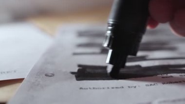 Hassas metnin üzerine yazılan siyah kalemden çok gizli kağıda yavaş bir pan. Belgenin gizliliğinin kaldırılması ve yayınlanmasından önce satırların karartılması ve sansürlenmesi üzerine işaretleyiciyi kapat