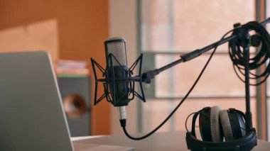 Bilgisayarlı mikrofon ve kulaklıklarla kayıt cihazlarını masaya doğru eğ. Video içeriği veya podcast şovu için ev kayıt stüdyosu. Profesyonel prosumer ekipmanları evdeki masada.