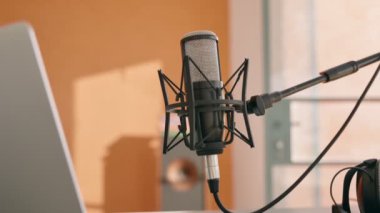 El kamerası, masadaki bilgisayarın yanındaki profesyonel mikrofona yaklaş. Evde kulaklıklı kayıt stüdyosu ve podcast ya da video içeriği şovu ya da uzaktan konuşma ya da sohbet için mikrofon