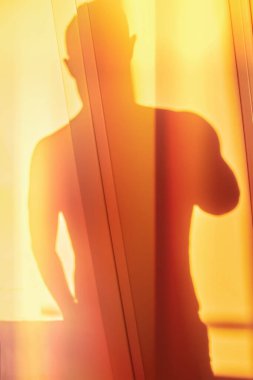 Shadow from upper body of unknown young man in glistening beautiful orange yellow sunlight, conceptual silhouette photo
